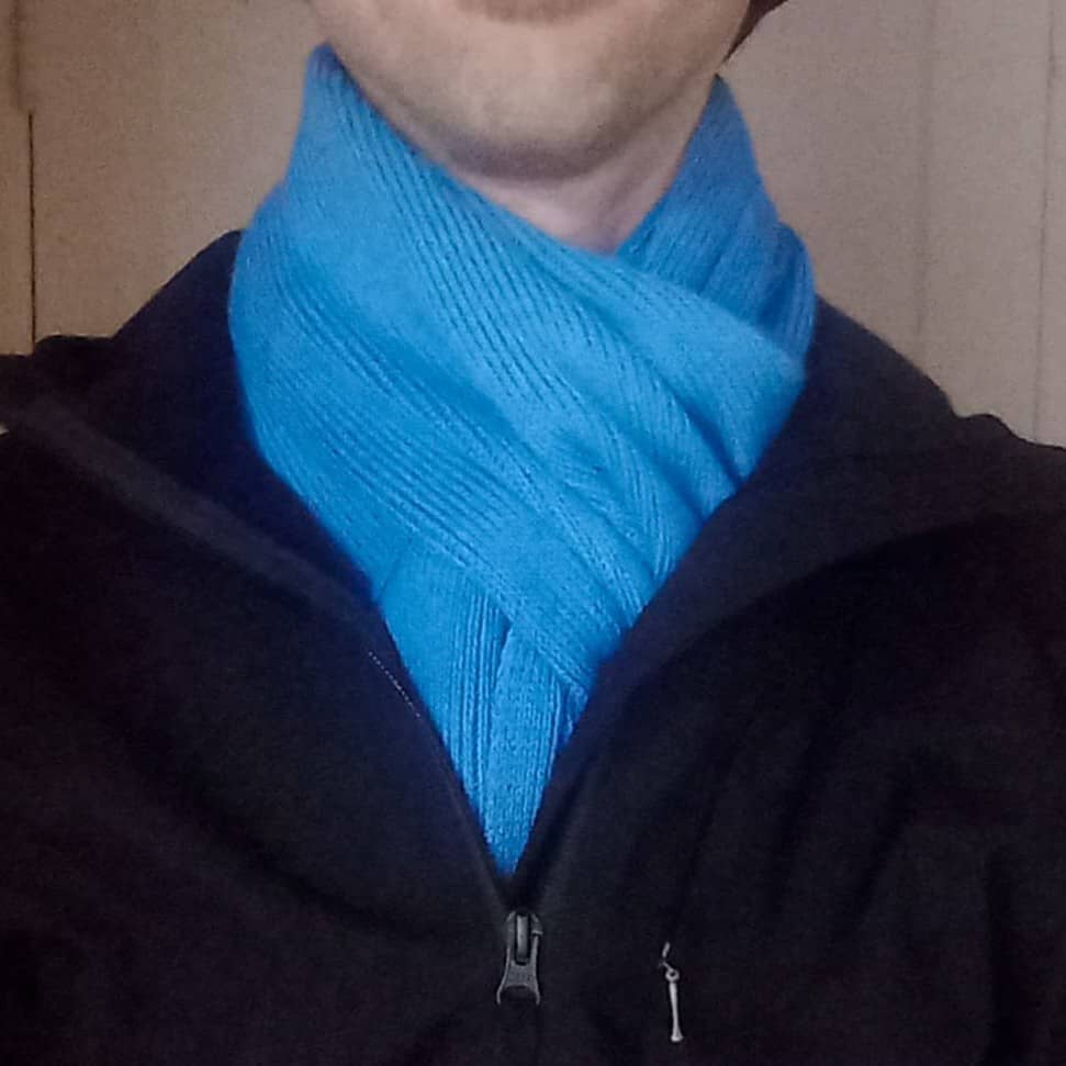 A close-up shot of a person wearing a bright blue merino wool knit scarf.