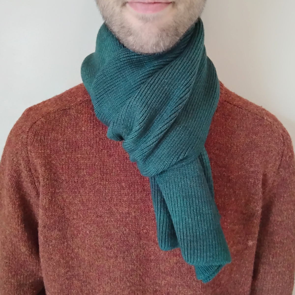 A forest green knit scarf on a model.