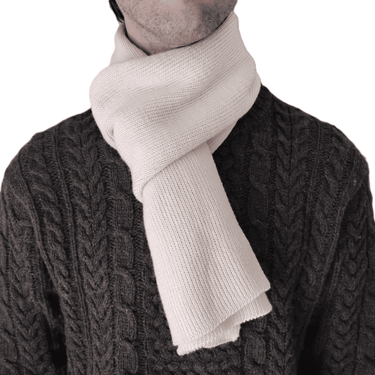 A close-up of a person wearing a thick, cream-colored knit merino wool scarf.