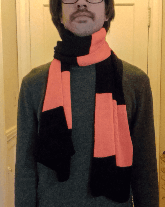 Person wearing a black and orange scarf in front of a neutral background