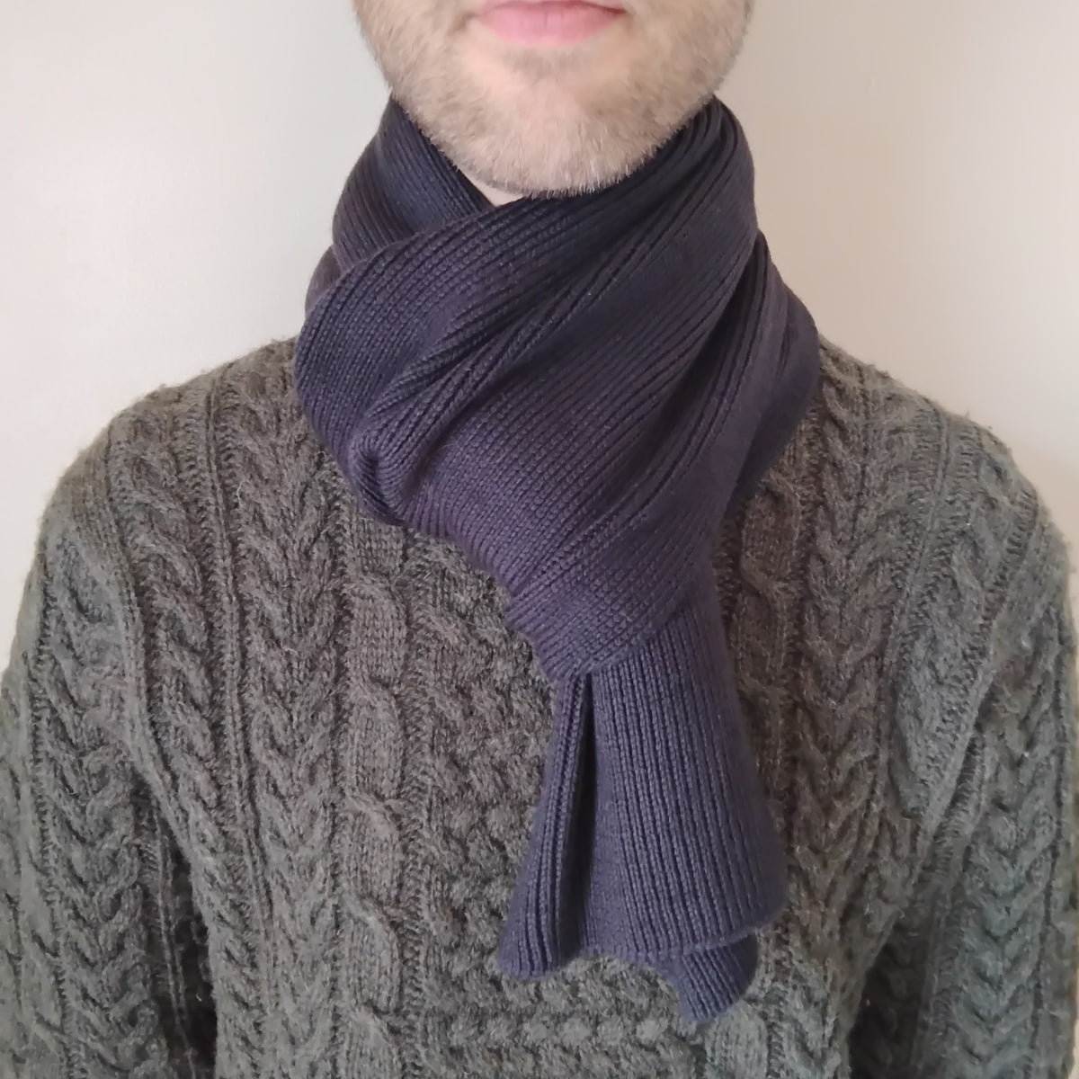 A dark charcoal gray knit scarf on a model.