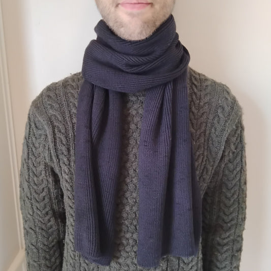 A dark charcoal gray knit scarf wrapped around a model.
