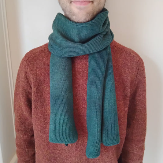 A forest green knit scarf wrapped around a model.