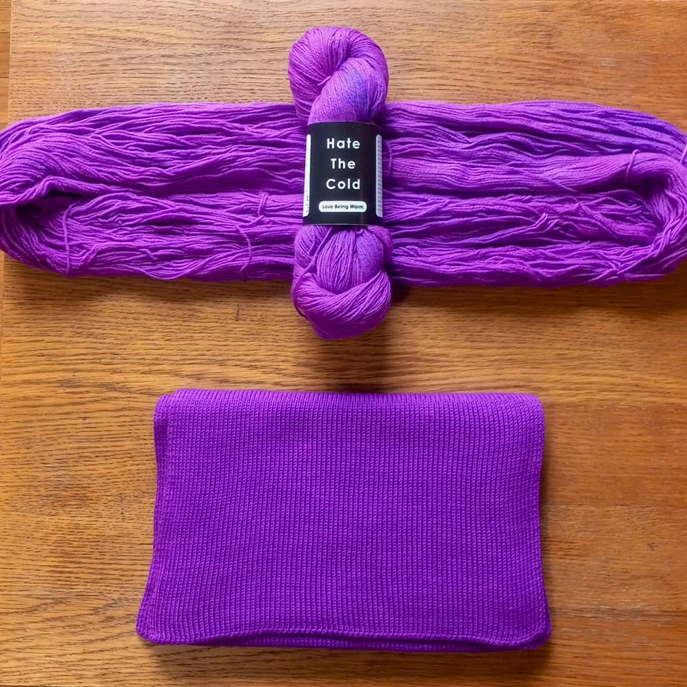 A purple knit scarf and a matching skein wrapped with a label that reads 'Hate The Cold' and 'comfortwe'.