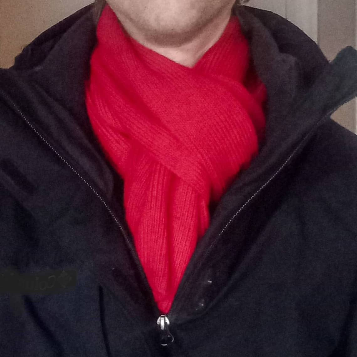 A close-up shot of a person wearing a bright red merino wool knit scarf.